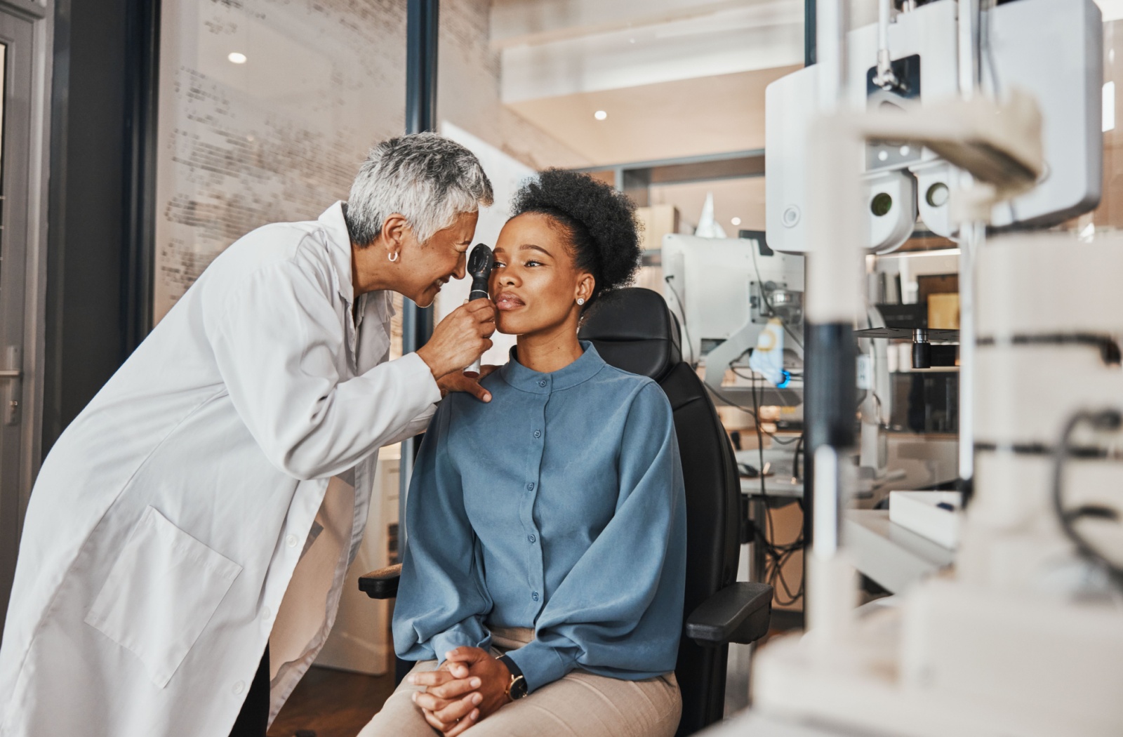 A young woman getting an eye exam from her female optometrist.