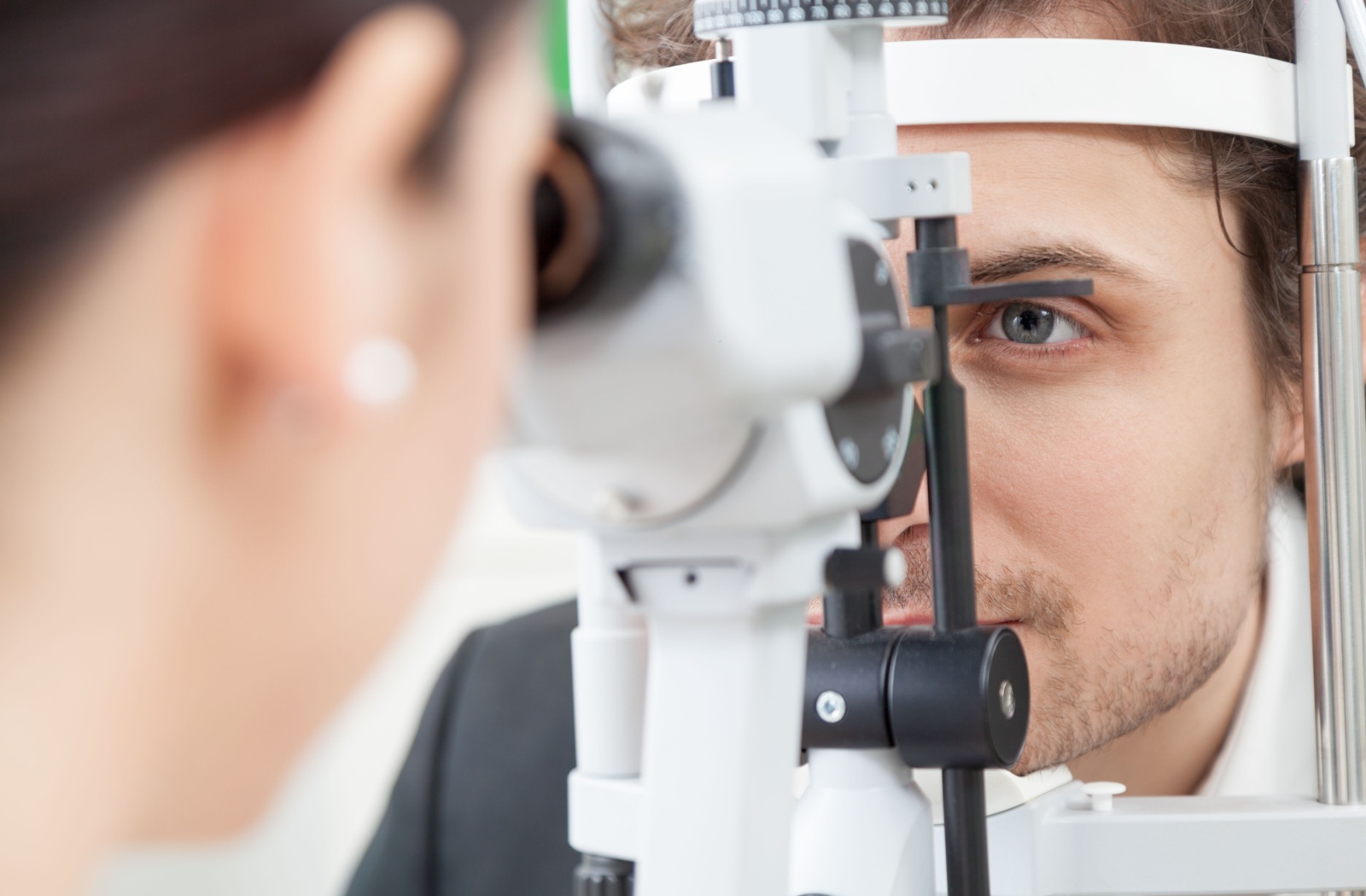 An optometrist examines her patient's eyes for sun damage.