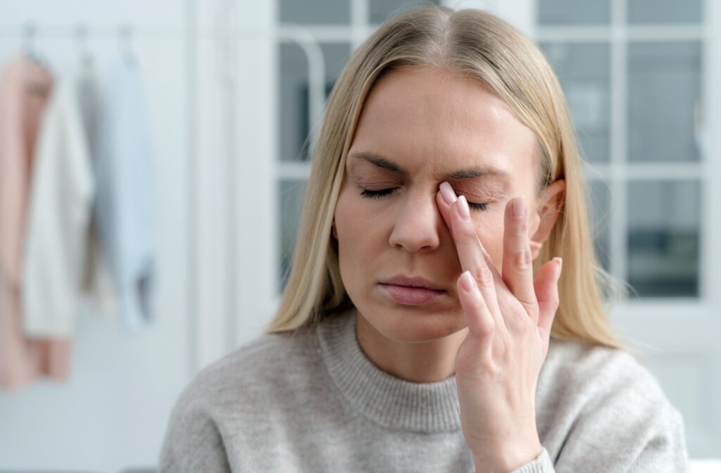 A blond woman rubbing her left eye in frustration due to the discomfort from her pink eye.