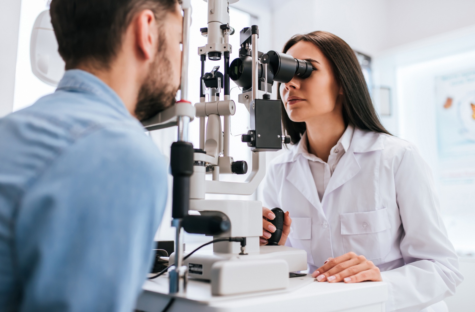 An optometrist examining a patient's eyes during an eye exam to diagnose his pink eye.