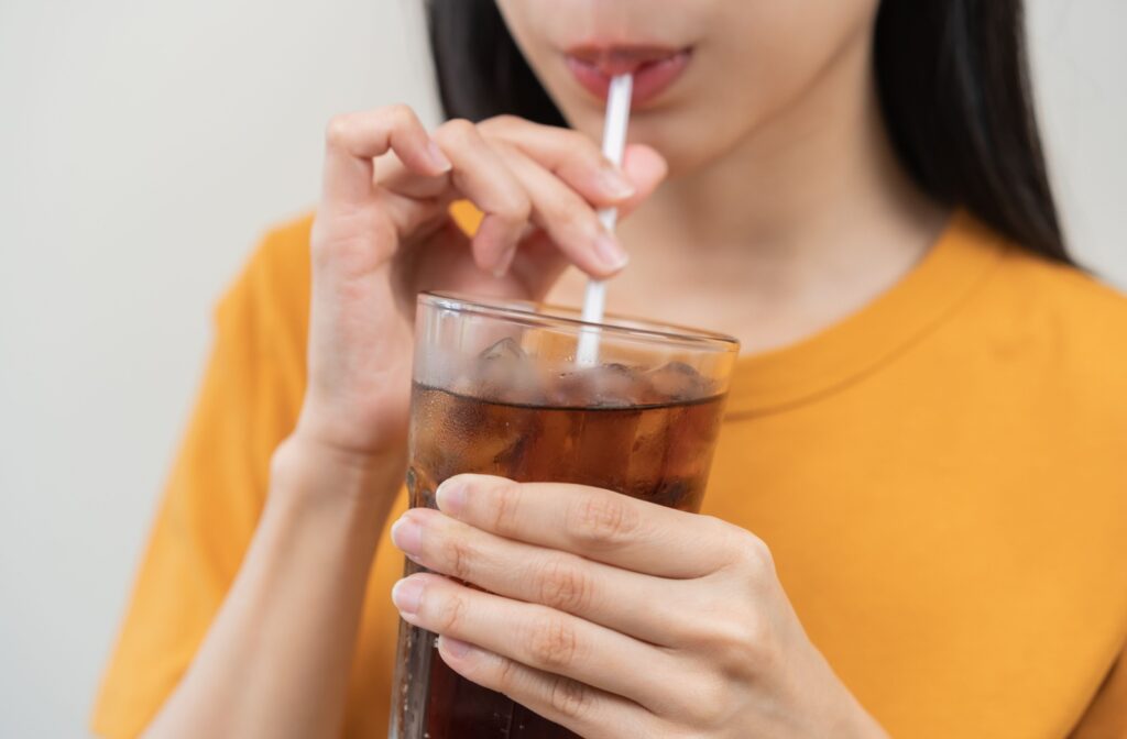 A cropped photo of a woman drinking a sugary soda.