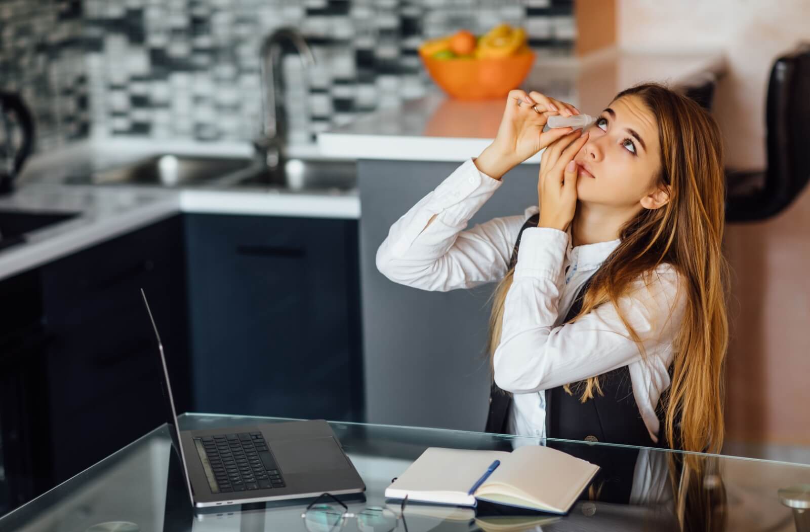 A young business professional applies eye drops before a morning meeting after waking with dry eye symptoms