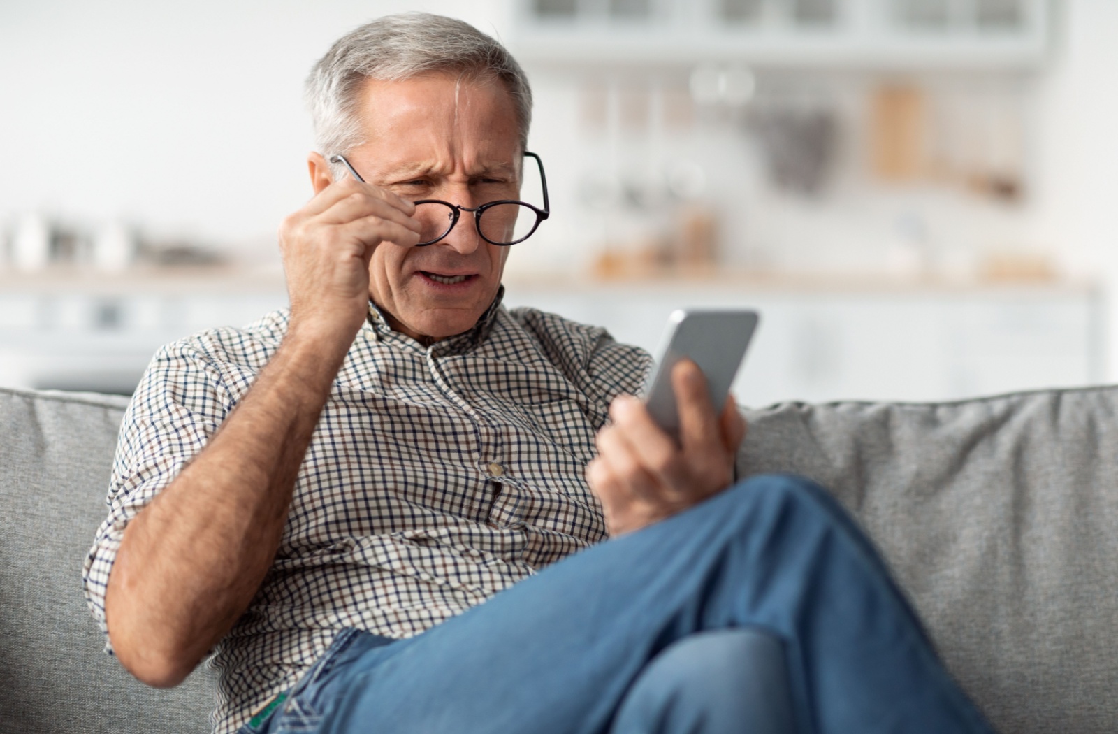 Man with 20/40 vision holding smartphone and squinting to read small text.