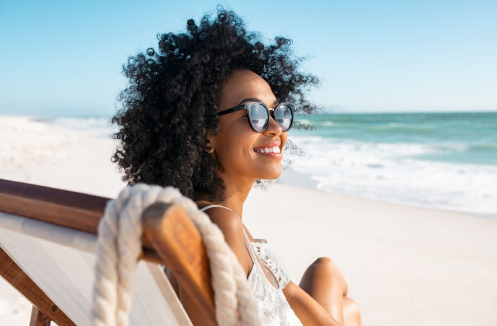 A person on a lounge chair at the beach wearing sunglasses.