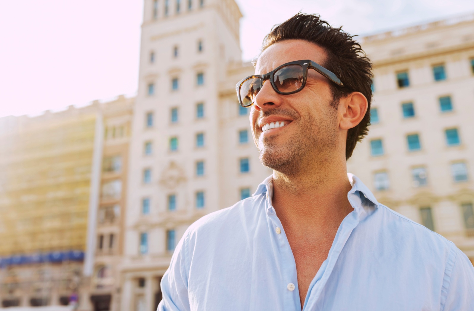 A person outdoors in the city wearing sunglasses.