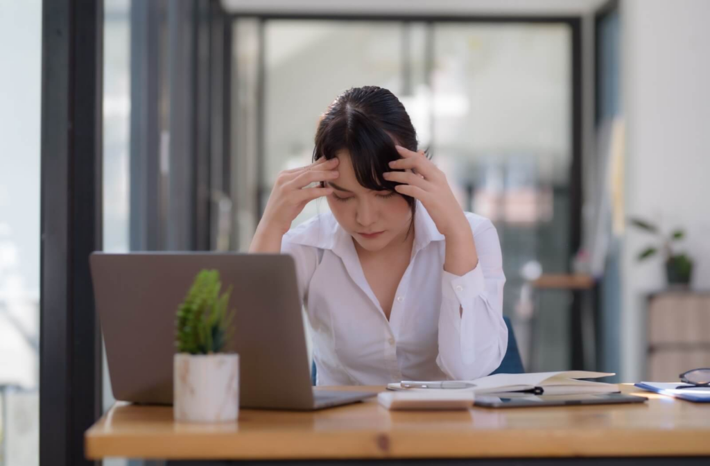 Person experiencing a headache while working at a their desk.